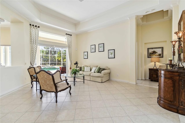 living area with a raised ceiling, ornamental molding, a sunroom, light tile patterned floors, and baseboards