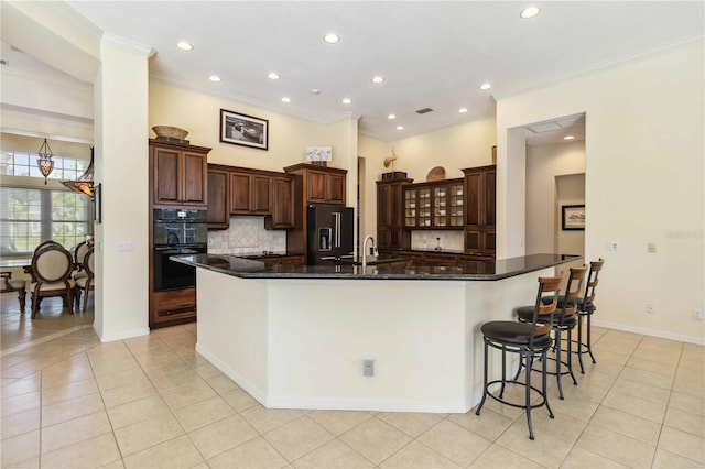 kitchen featuring tasteful backsplash, crown molding, a breakfast bar, a large island, and black appliances