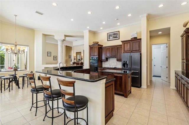 kitchen with light tile patterned floors, high quality fridge, a kitchen island with sink, and a sink