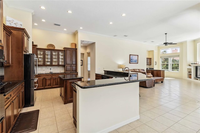 kitchen featuring a spacious island, dark countertops, open floor plan, light tile patterned flooring, and decorative backsplash