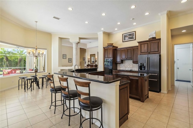 kitchen featuring an island with sink, high end fridge, light tile patterned floors, and a sink