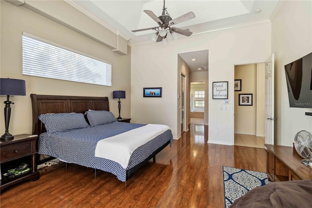 bedroom featuring a ceiling fan, crown molding, wood finished floors, and baseboards