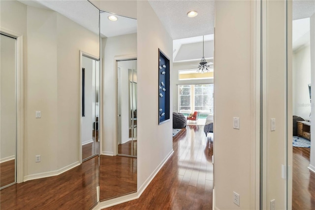 hallway featuring recessed lighting, baseboards, a textured ceiling, and wood finished floors