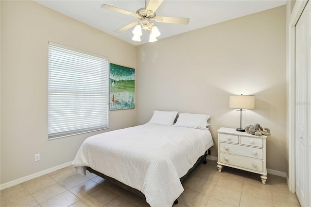 bedroom featuring light tile patterned floors, baseboards, and a closet