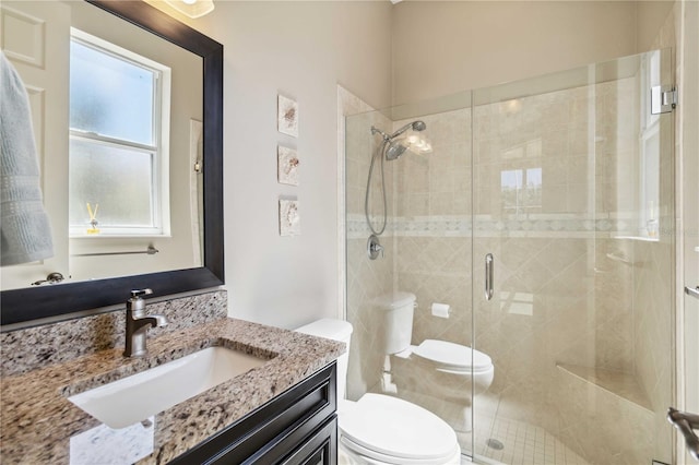 bathroom featuring vanity, a shower stall, and toilet