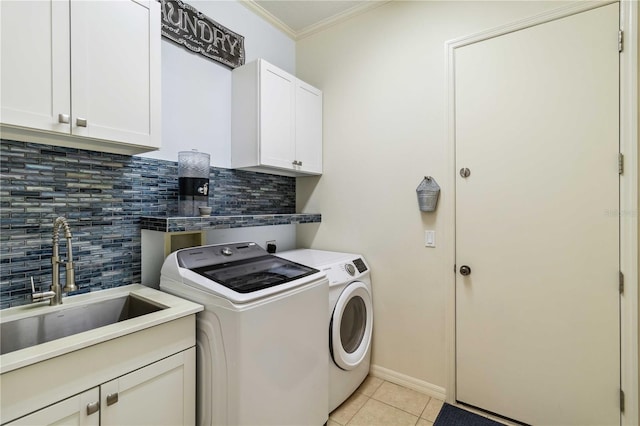 laundry room featuring a sink, washing machine and dryer, cabinet space, light tile patterned flooring, and crown molding