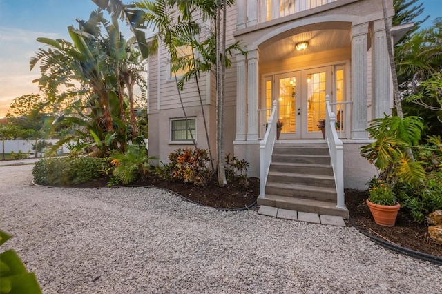 exterior entry at dusk featuring stucco siding and french doors