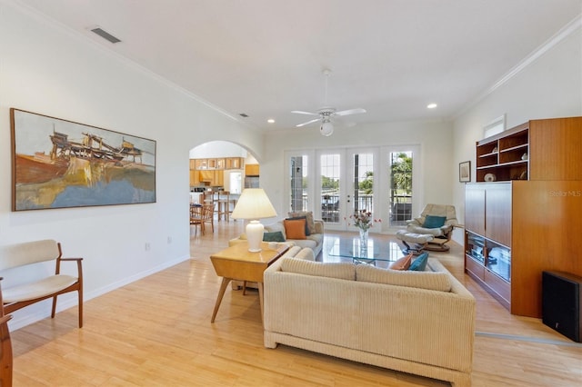 living area with visible vents, crown molding, baseboards, light wood-type flooring, and arched walkways