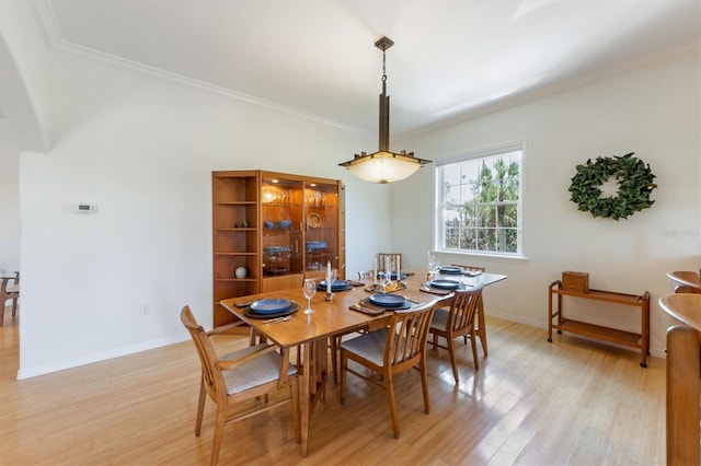 dining space featuring baseboards, crown molding, and light wood finished floors