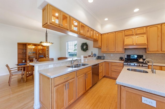 kitchen featuring a sink, light wood-style flooring, appliances with stainless steel finishes, and a peninsula