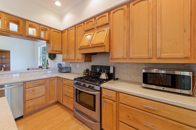 kitchen with premium range hood, light wood-type flooring, ornamental molding, backsplash, and stainless steel appliances