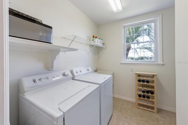 laundry area featuring light tile patterned floors, laundry area, washing machine and dryer, and baseboards