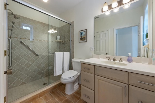 bathroom with vanity, a shower stall, and toilet