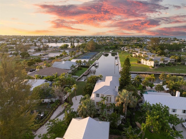 aerial view at dusk featuring a water view and a residential view