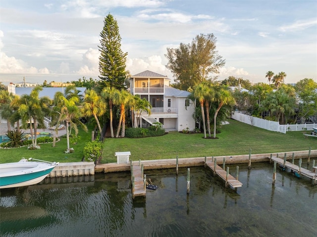 view of dock with stairway, a lawn, fence, and a water view