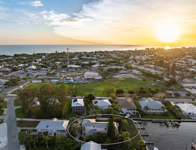 aerial view at dusk with a water view and a residential view