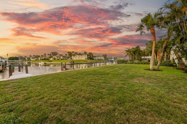 exterior space featuring a boat dock, a lawn, a water view, and boat lift