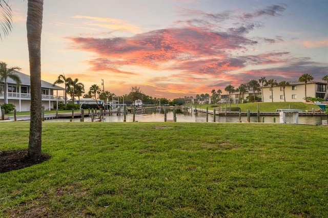 view of home's community featuring a yard, a water view, and a boat dock