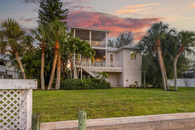 back of property featuring stairway, a lawn, metal roof, and fence