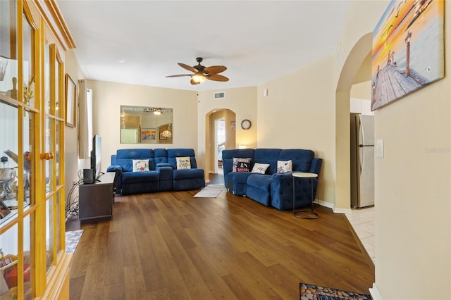 living room with baseboards, visible vents, arched walkways, ceiling fan, and light wood-type flooring