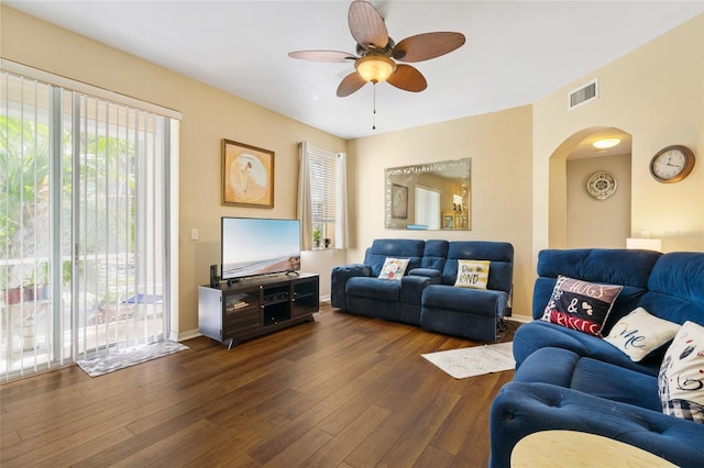 living room featuring baseboards, visible vents, arched walkways, ceiling fan, and dark wood-type flooring