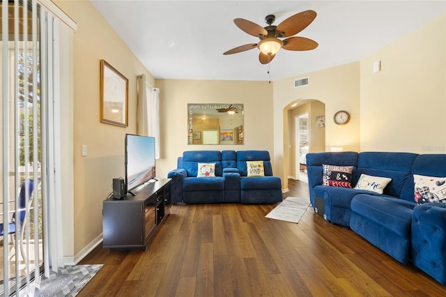 living area featuring visible vents, arched walkways, plenty of natural light, and wood-type flooring