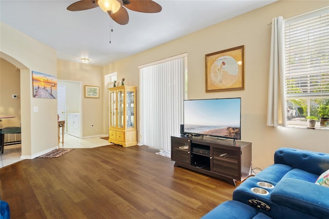 living area with baseboards, arched walkways, a ceiling fan, and hardwood / wood-style flooring