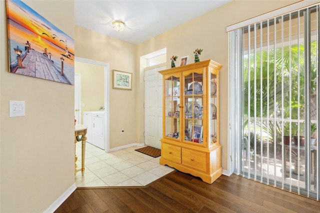 entrance foyer with wood finished floors, baseboards, and washing machine and clothes dryer