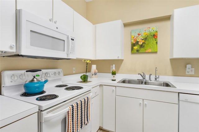 kitchen featuring white appliances, white cabinets, light countertops, and a sink