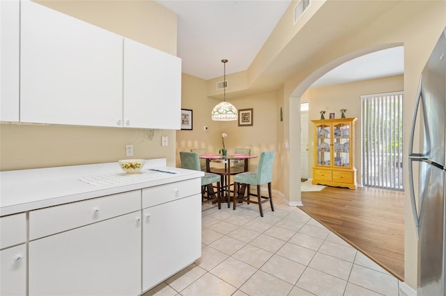 kitchen with visible vents, light countertops, light tile patterned floors, freestanding refrigerator, and arched walkways