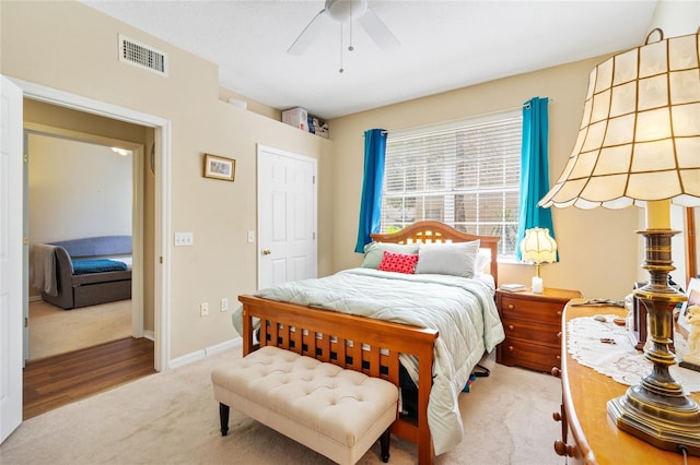 carpeted bedroom featuring a ceiling fan, visible vents, and baseboards