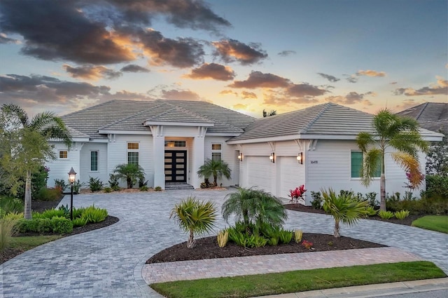 prairie-style home with a tiled roof, french doors, decorative driveway, and a garage