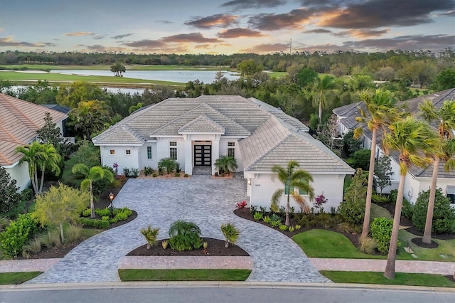 view of front of property with decorative driveway, a water view, and a tile roof