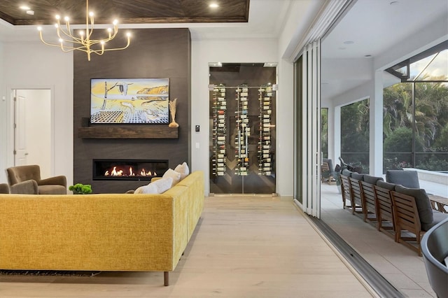 living room with crown molding, wood finished floors, a chandelier, and a large fireplace