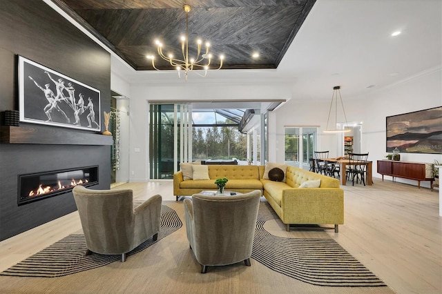 living area featuring a notable chandelier, a glass covered fireplace, wood finished floors, recessed lighting, and crown molding