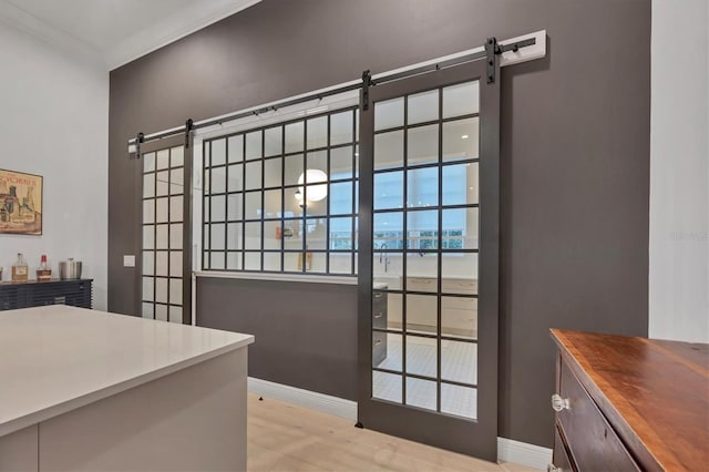 doorway with a barn door, light wood-style flooring, and baseboards