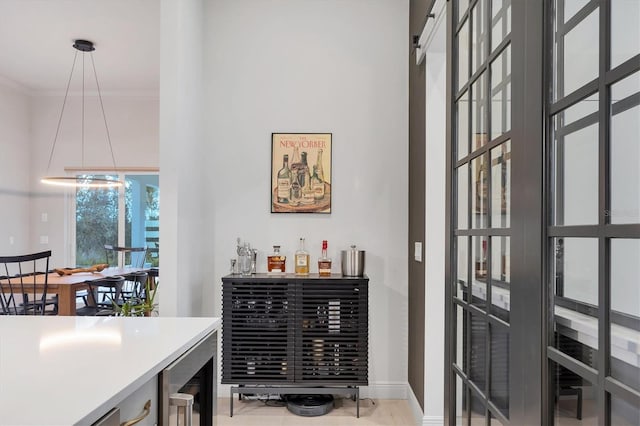 bar with beverage cooler, baseboards, and ornamental molding