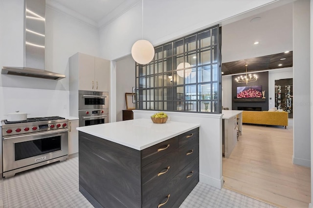 kitchen featuring an inviting chandelier, stainless steel appliances, light countertops, crown molding, and wall chimney range hood