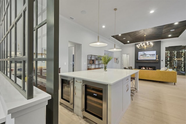 kitchen with a tray ceiling, visible vents, wine cooler, and crown molding