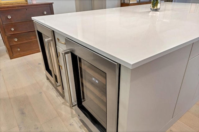 interior details featuring light countertops, beverage cooler, light wood finished floors, and a center island