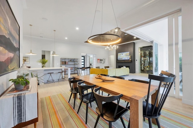 dining space with light wood-style flooring, plenty of natural light, a chandelier, and ornamental molding