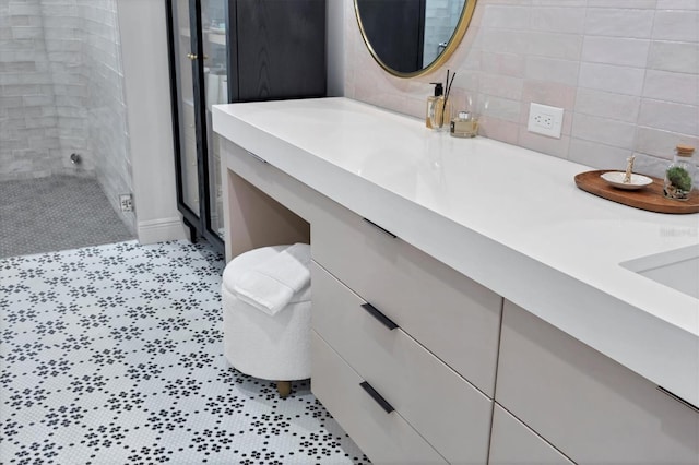 full bathroom with double vanity, decorative backsplash, and a shower stall