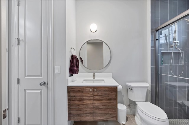 full bath featuring a tile shower, tile patterned flooring, toilet, and vanity