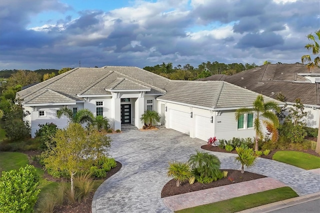 view of front of home featuring a tile roof, decorative driveway, a garage, and stucco siding