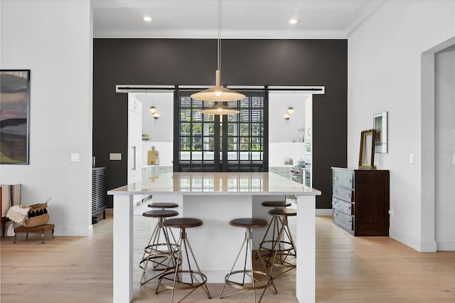 kitchen with light countertops, light wood-style flooring, crown molding, and a kitchen breakfast bar