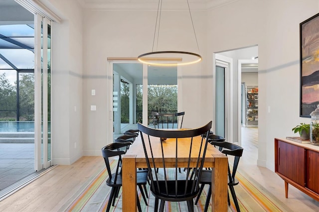 dining space featuring light wood-style flooring, a healthy amount of sunlight, baseboards, and ornamental molding