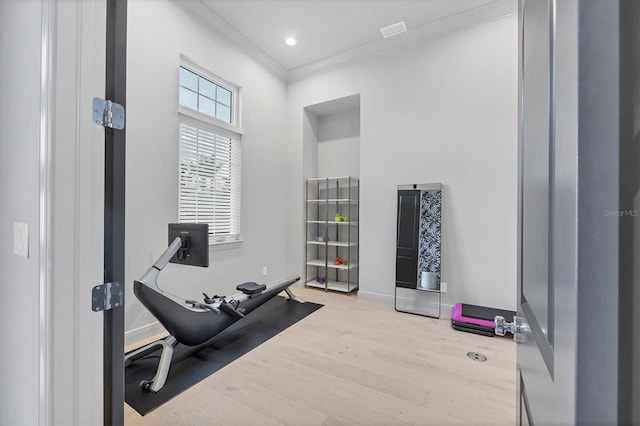 workout room with baseboards, crown molding, wood finished floors, and visible vents