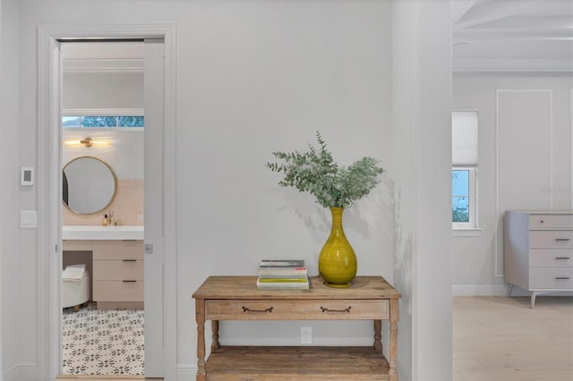 hall featuring baseboards, wood finished floors, and a sink