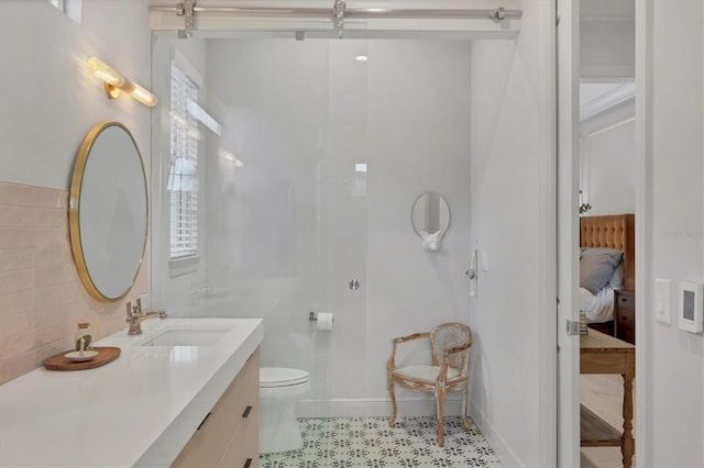 bathroom with toilet, vanity, baseboards, tasteful backsplash, and ensuite bathroom