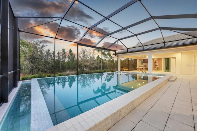 view of pool with glass enclosure, an infinity pool, and a patio